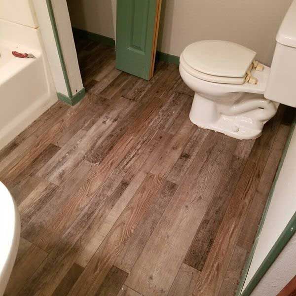 Bathroom with weathered wood-look flooring, toilet, shower, and green trim.