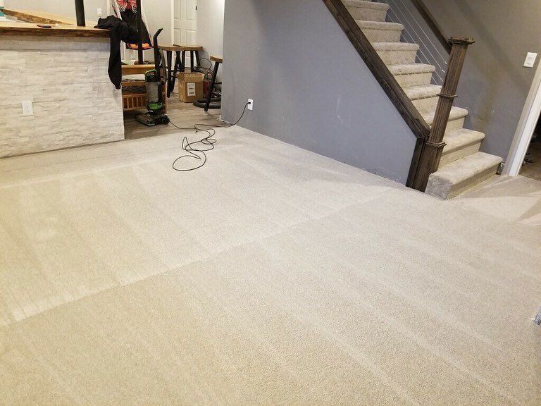Beige carpeted basement with stairs and a bar area.