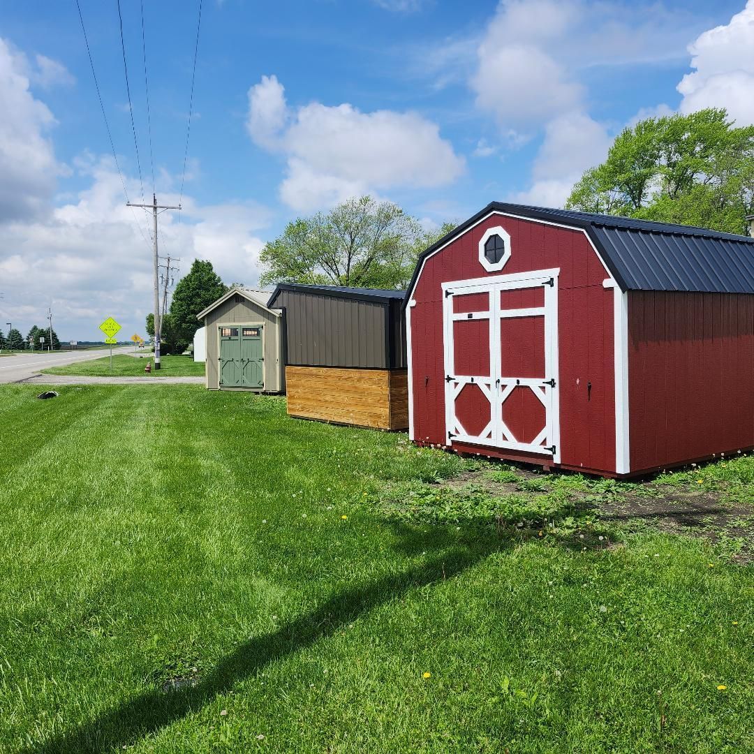 A small red barn shed on green grass