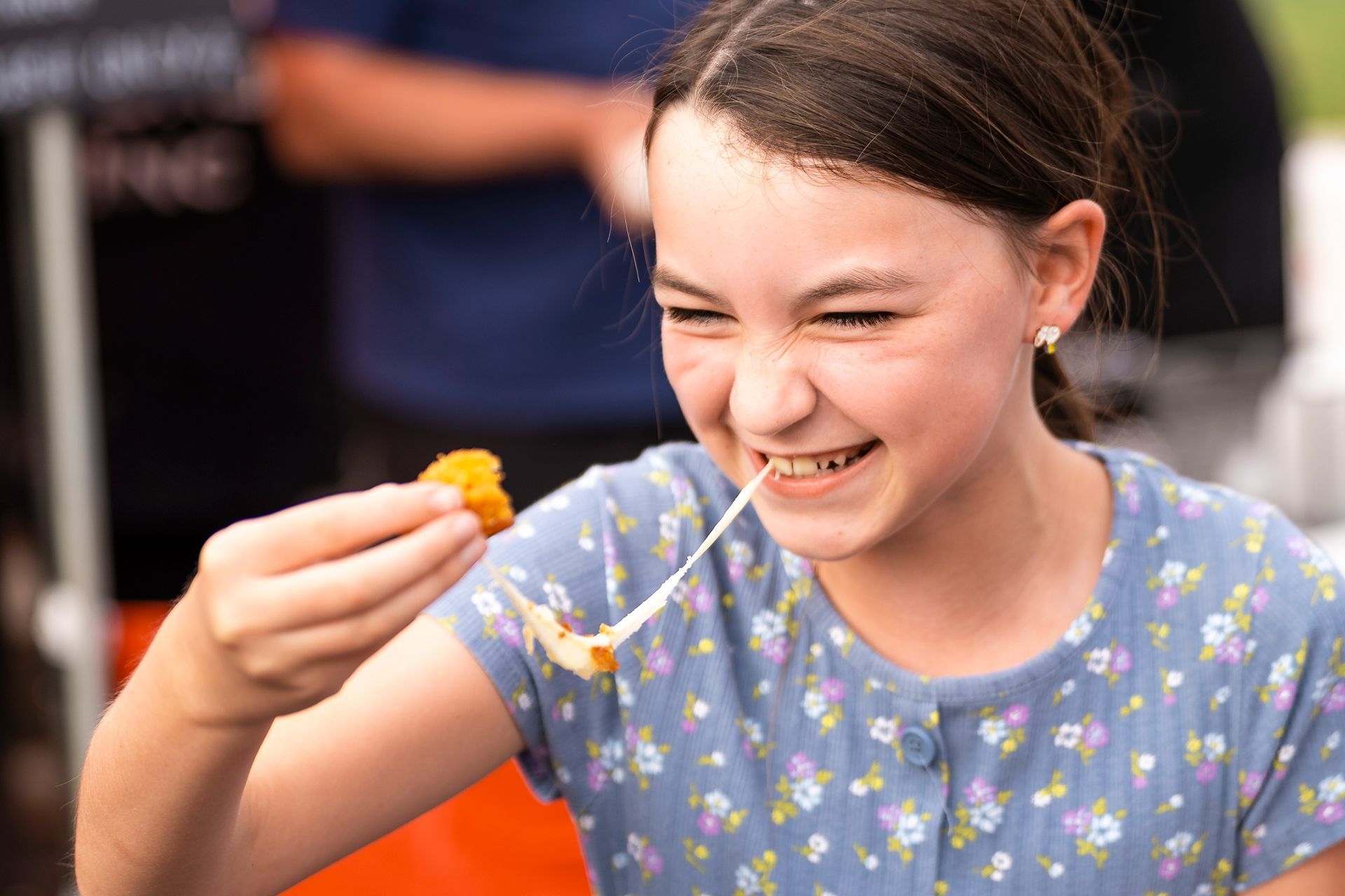 A young girl is pulling cheese