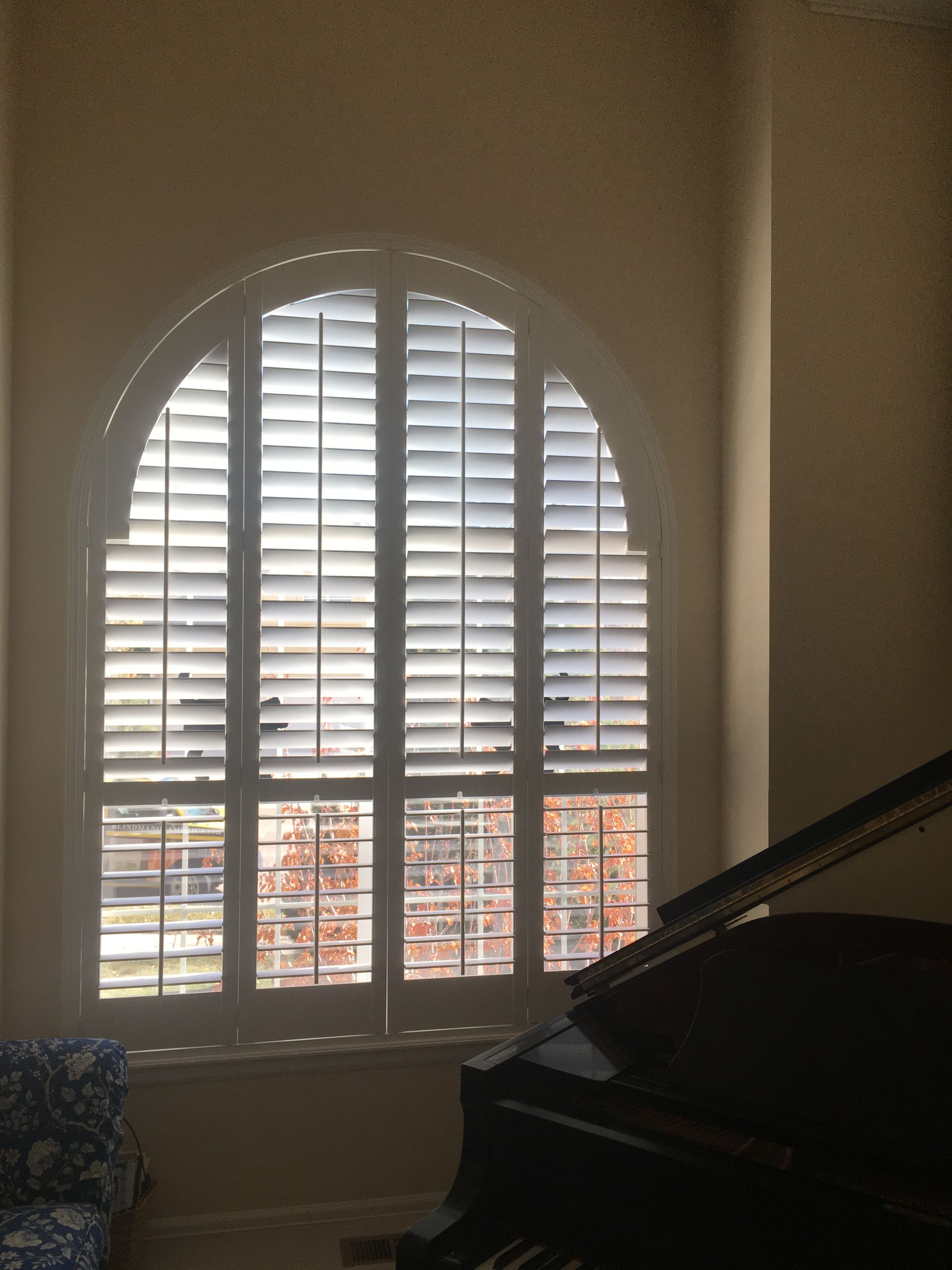 white arched plantation shutters installed in music room with grand piano in El Paso County