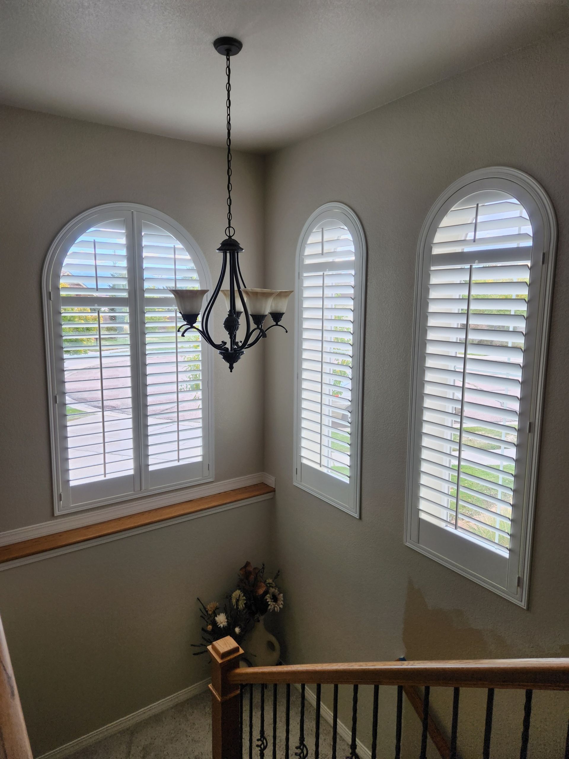 white plantation shutters installed in arched entryway near chandelier in Colorado Springs home