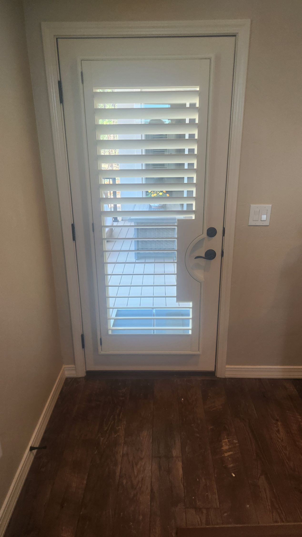 white plantation shutter installed on full glass back door with curved handle cutout in Colorado Springs home