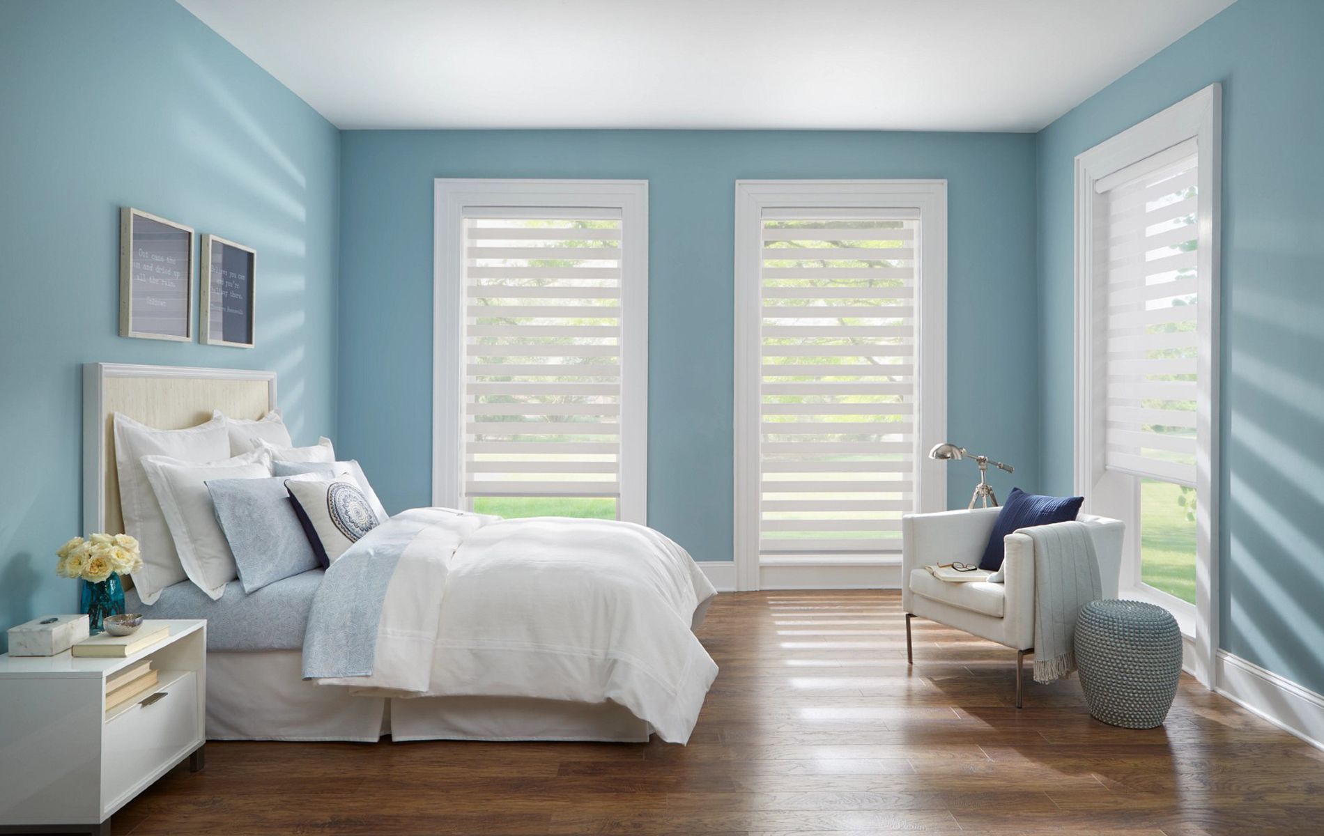 A bedroom with a bed , chair , nightstand and blue walls.