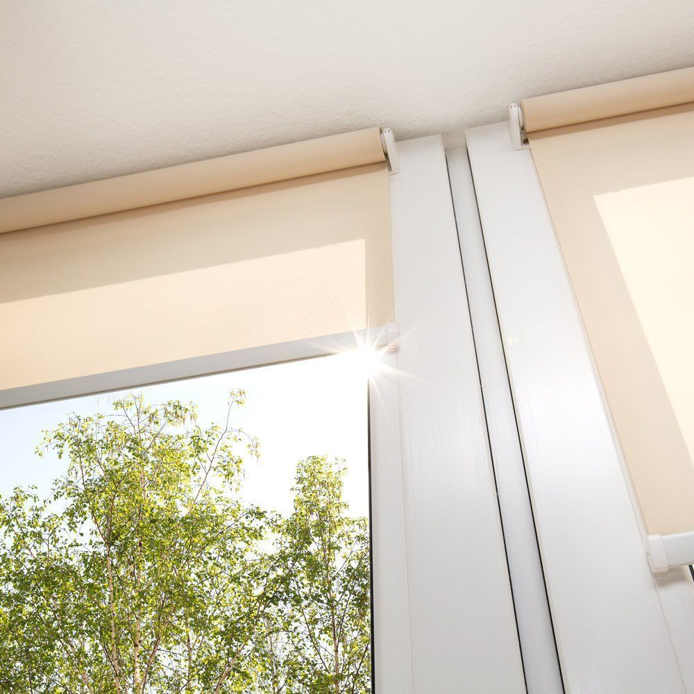 Motorized roller shades installed on large windows with cassette header, filtering sunlight