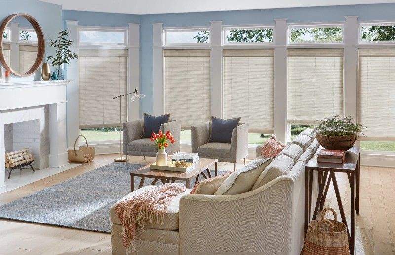 Dual-layered motorized shades in a bright, modern living room with multiple windows