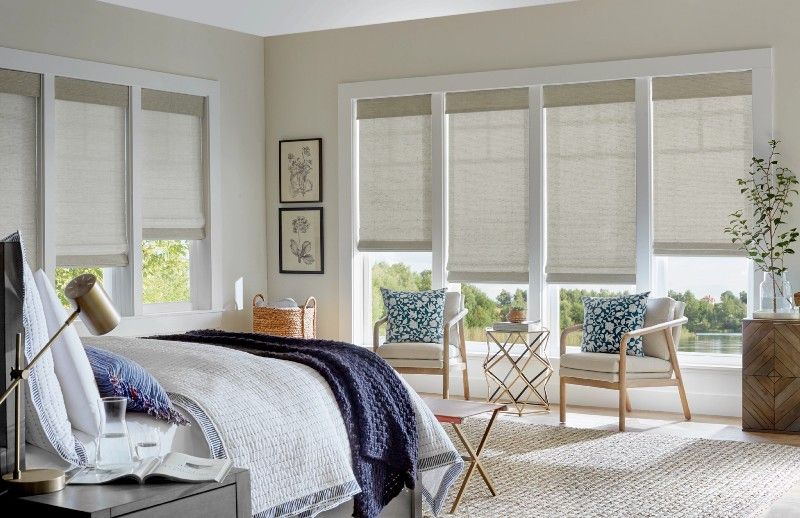 Neutral motorized shades over multiple bedroom windows with soft decor