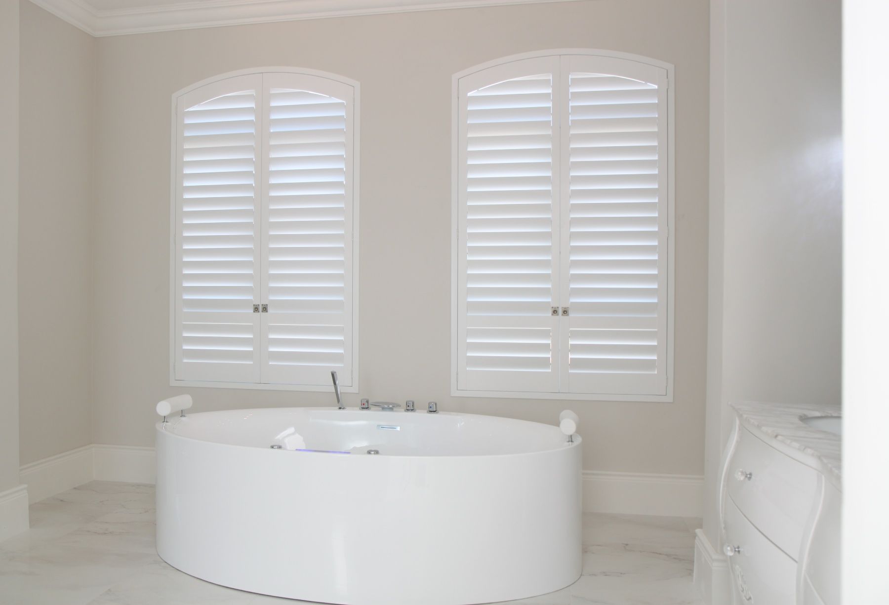 white plantation shutters installed above round tub in bathroom for privacy and natural light