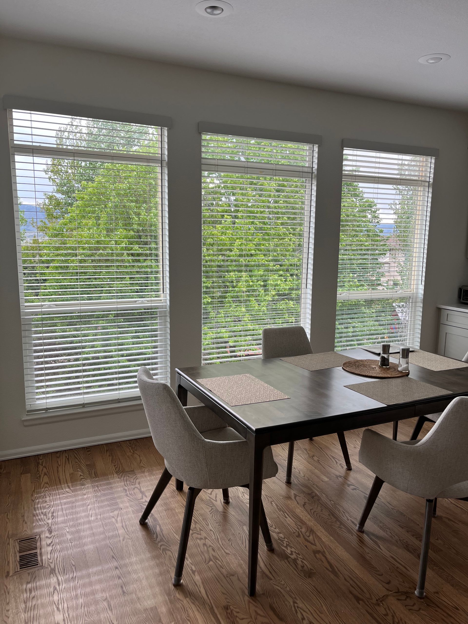 white horizontal blinds installed in dining room with wood flooring and modern furniture in Colorado Springs home