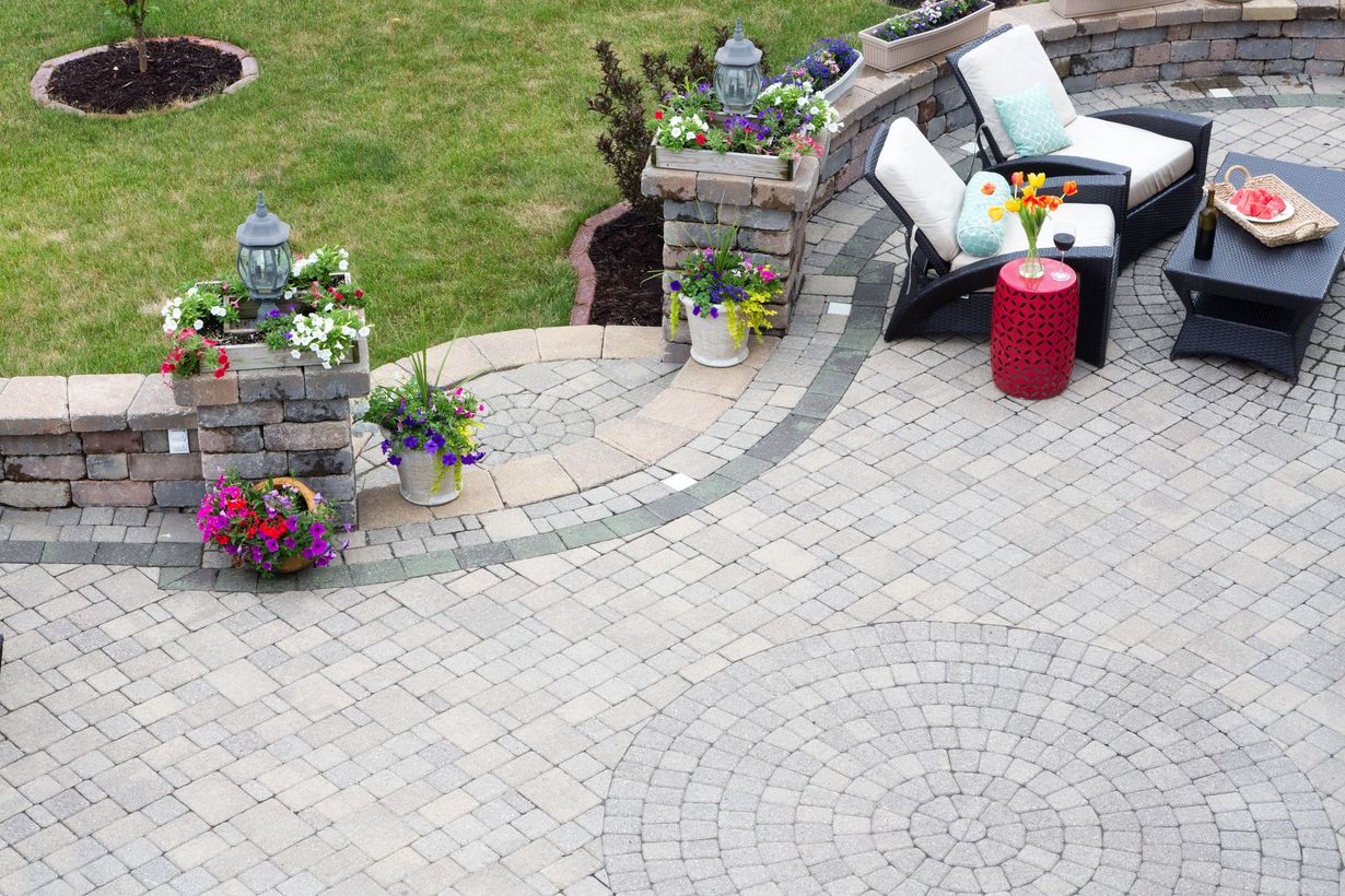 Patio with stone pavers, seating, and decorative plants.