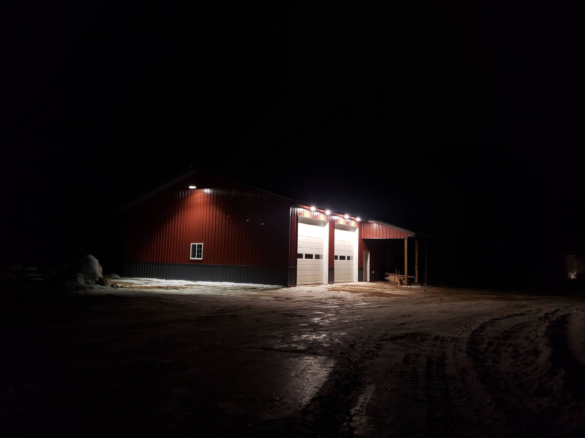 A red barn is lit up at night.