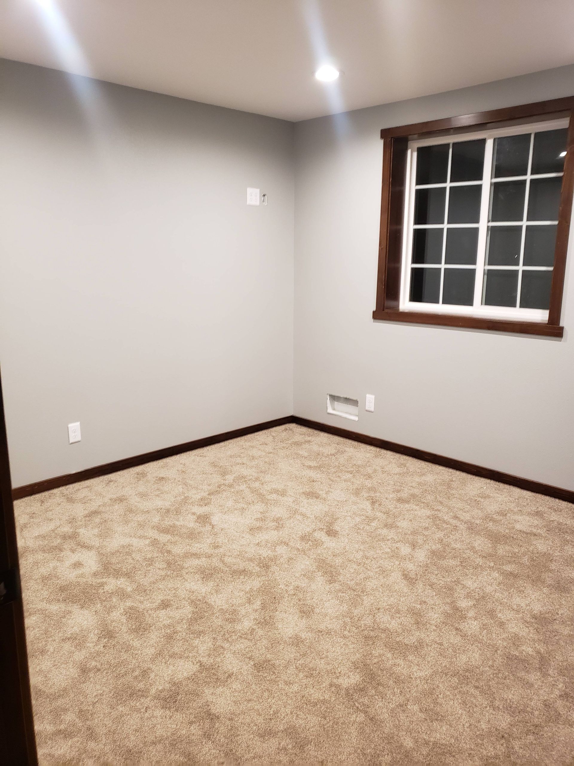An empty room with a window and a carpeted floor.