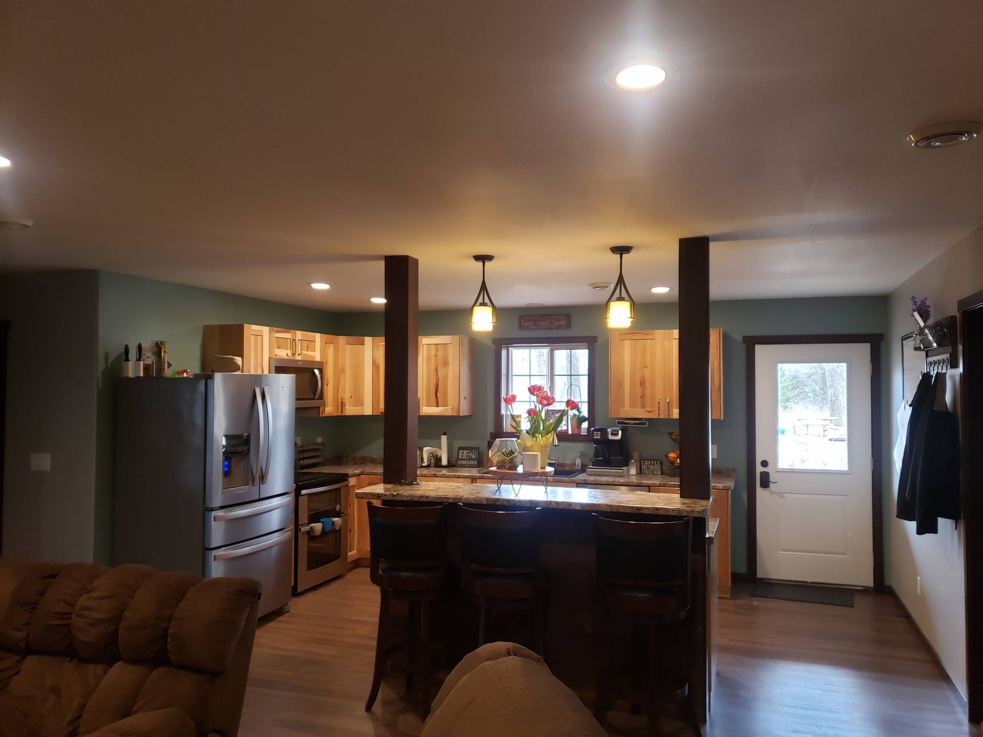 A living room with a couch and a kitchen with a refrigerator.