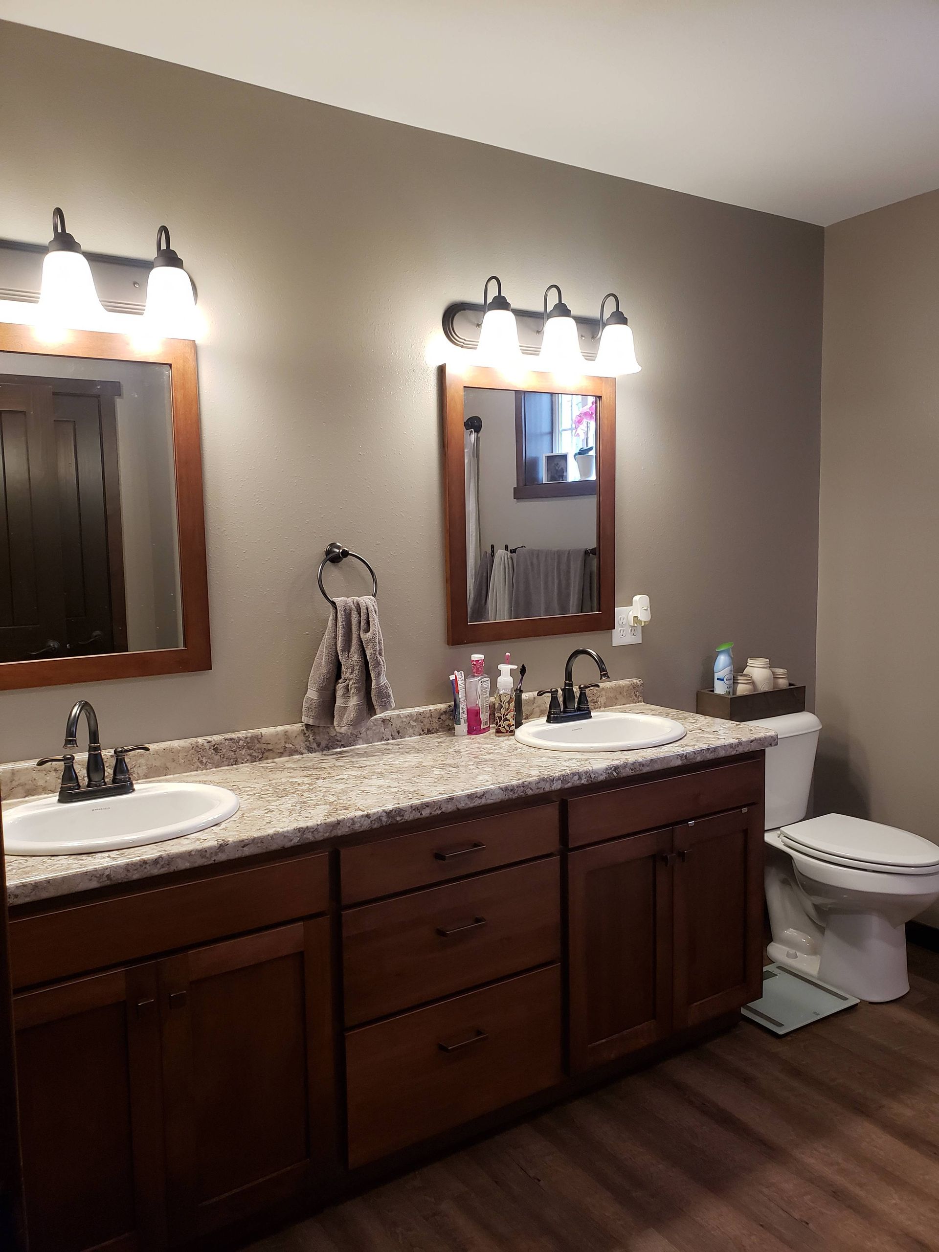 A bathroom with two sinks , a toilet and two mirrors.
