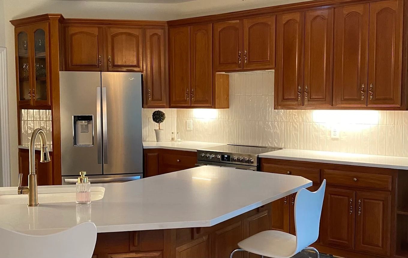 Modern kitchen with wooden cabinets, stainless steel fridge, and a large white island countertop