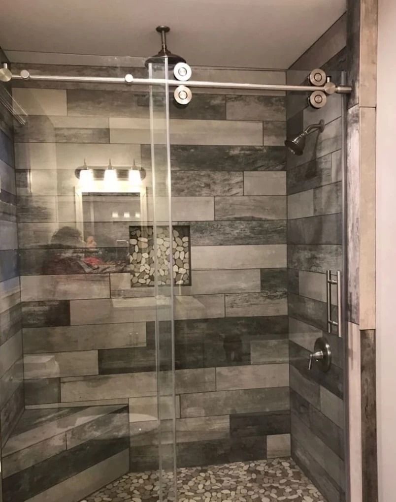 Glass shower with gray tile walls and sliding door in a bathroom