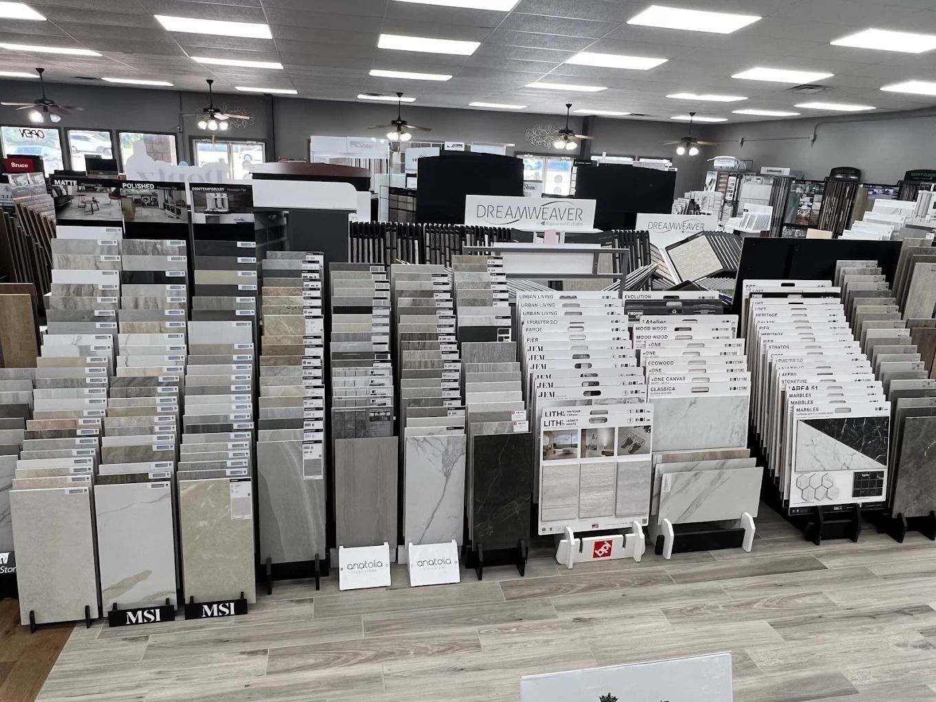 Store aisle with rows of display racks filled with boxed products under bright fluorescent lights