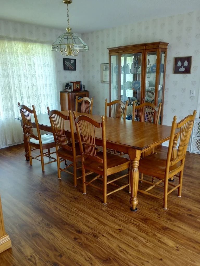 Dining room with wooden table and chairs, china cabinet, and hardwood floor.