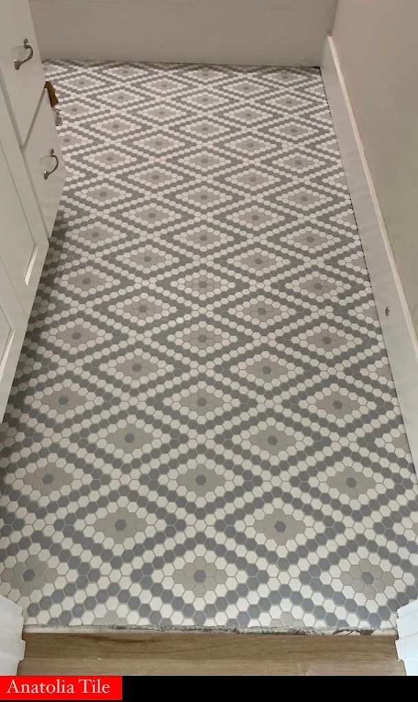 Narrow hallway with gray and white diamond-pattern tile floor and beige walls.