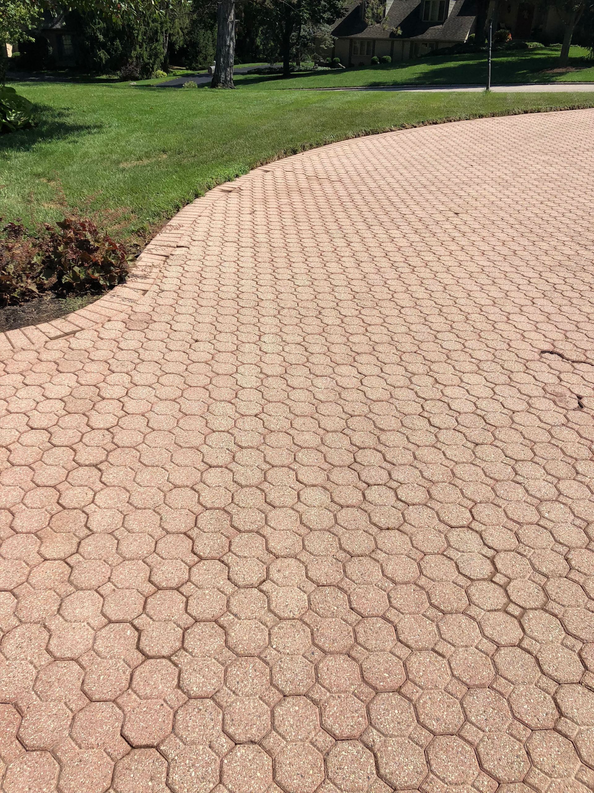 A brick walkway leading to a lush green field.