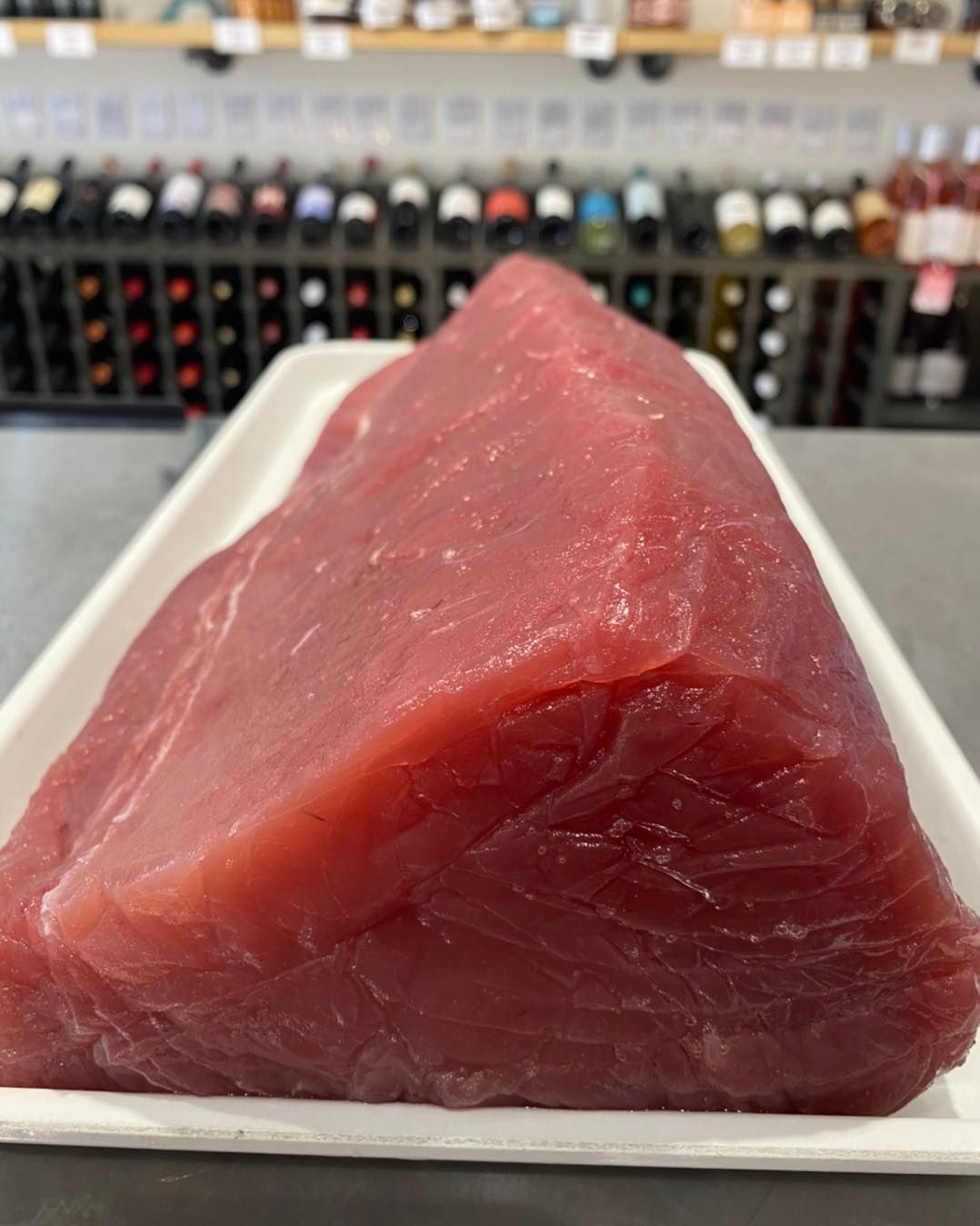 A large piece of red meat is on a white tray