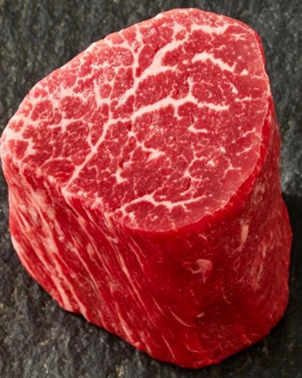A piece of red meat is sitting on a black surface