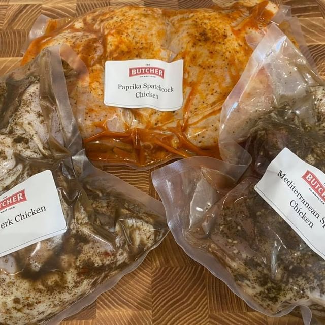 Three bags of chicken are sitting on a wooden table