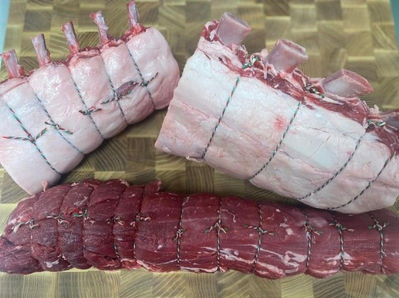 Two pieces of meat are sitting on a wooden cutting board.