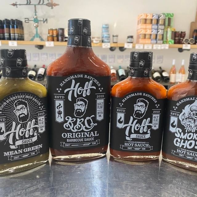 Several bottles of hot sauce are lined up on a table