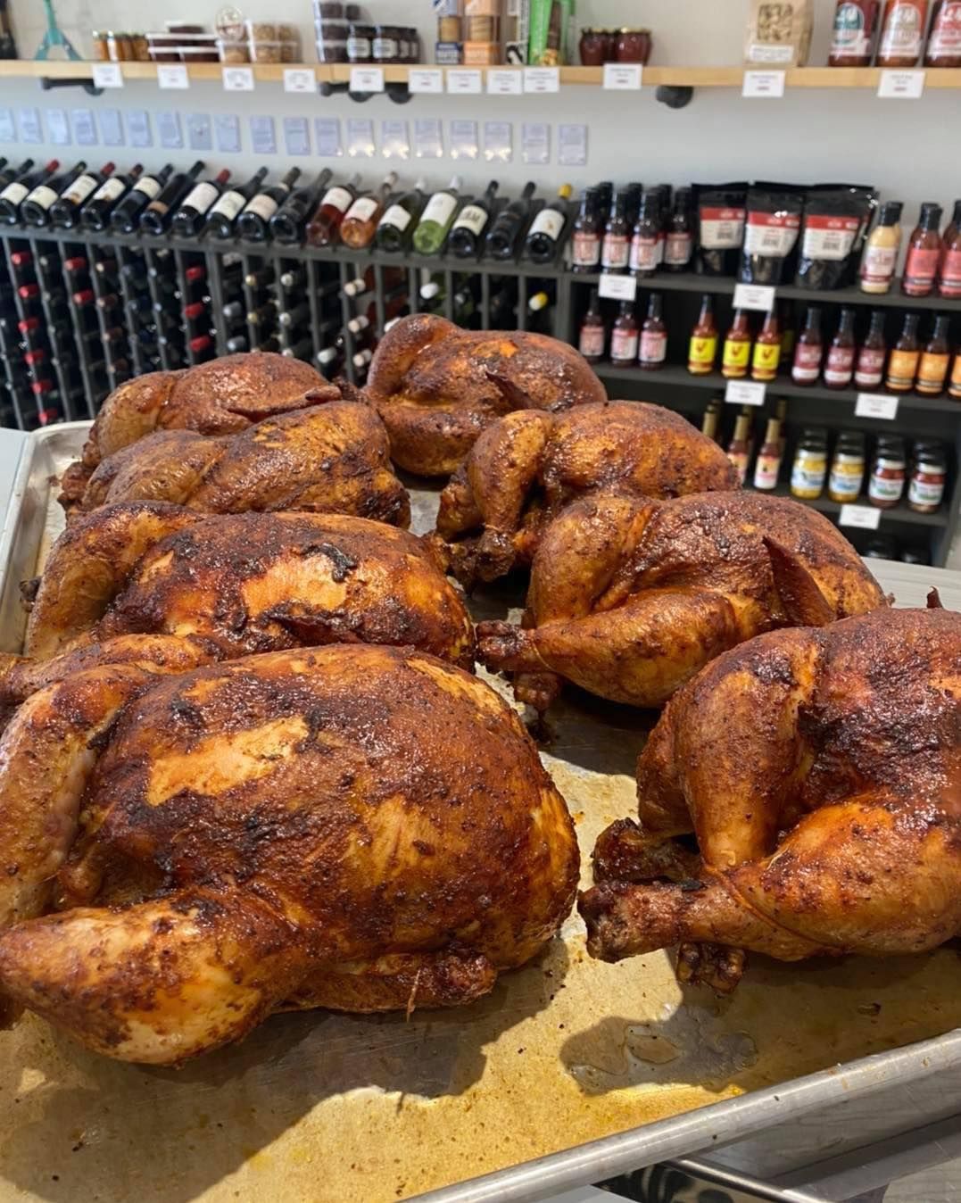 A bunch of roasted chickens are sitting on a pan in a store.