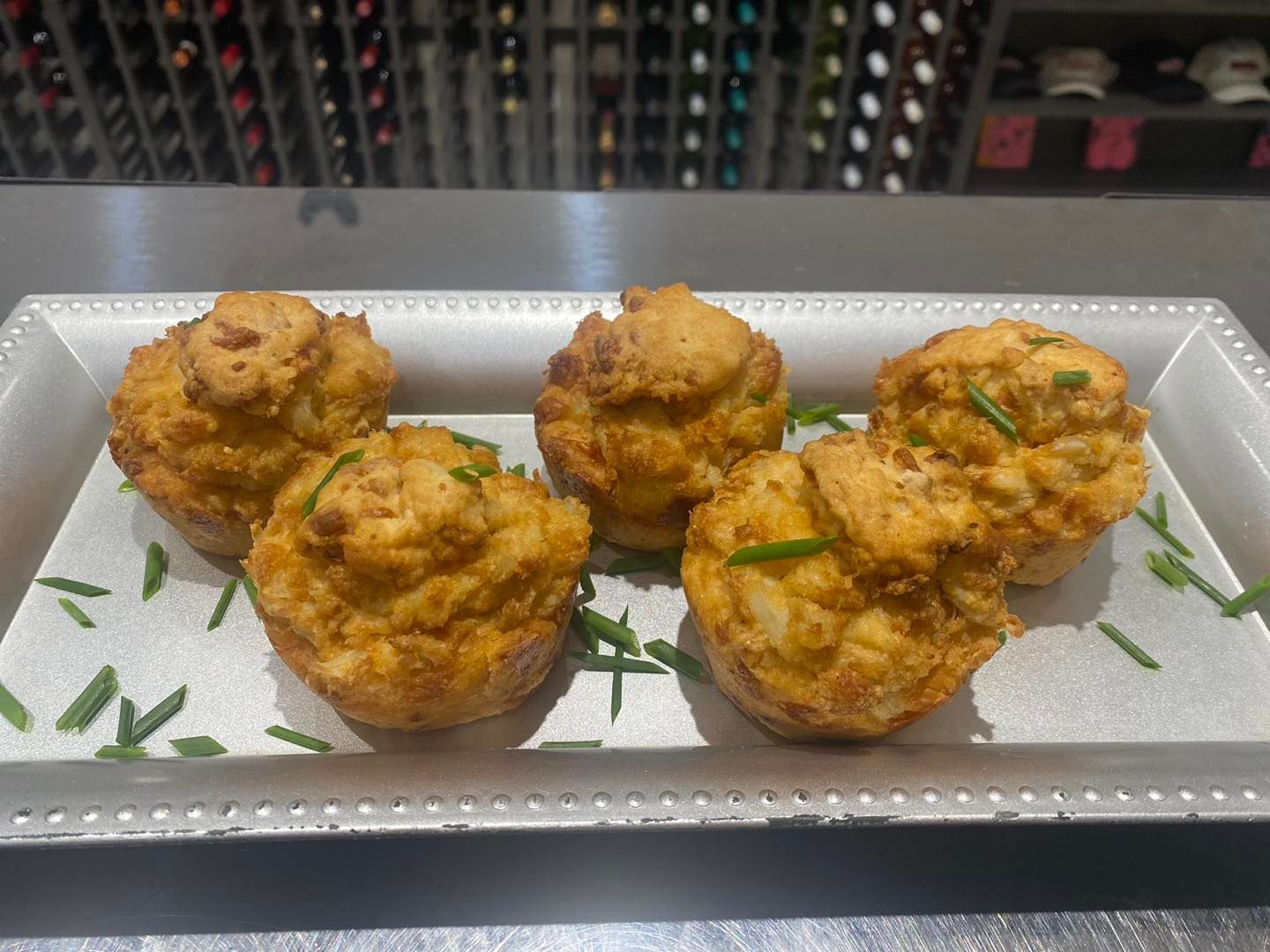 A tray of muffins with green onions on a table.