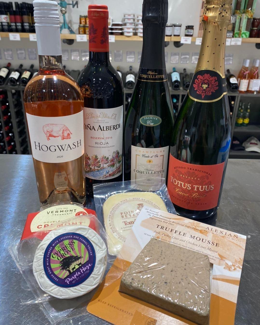 A table topped with bottles of wine and cheese.