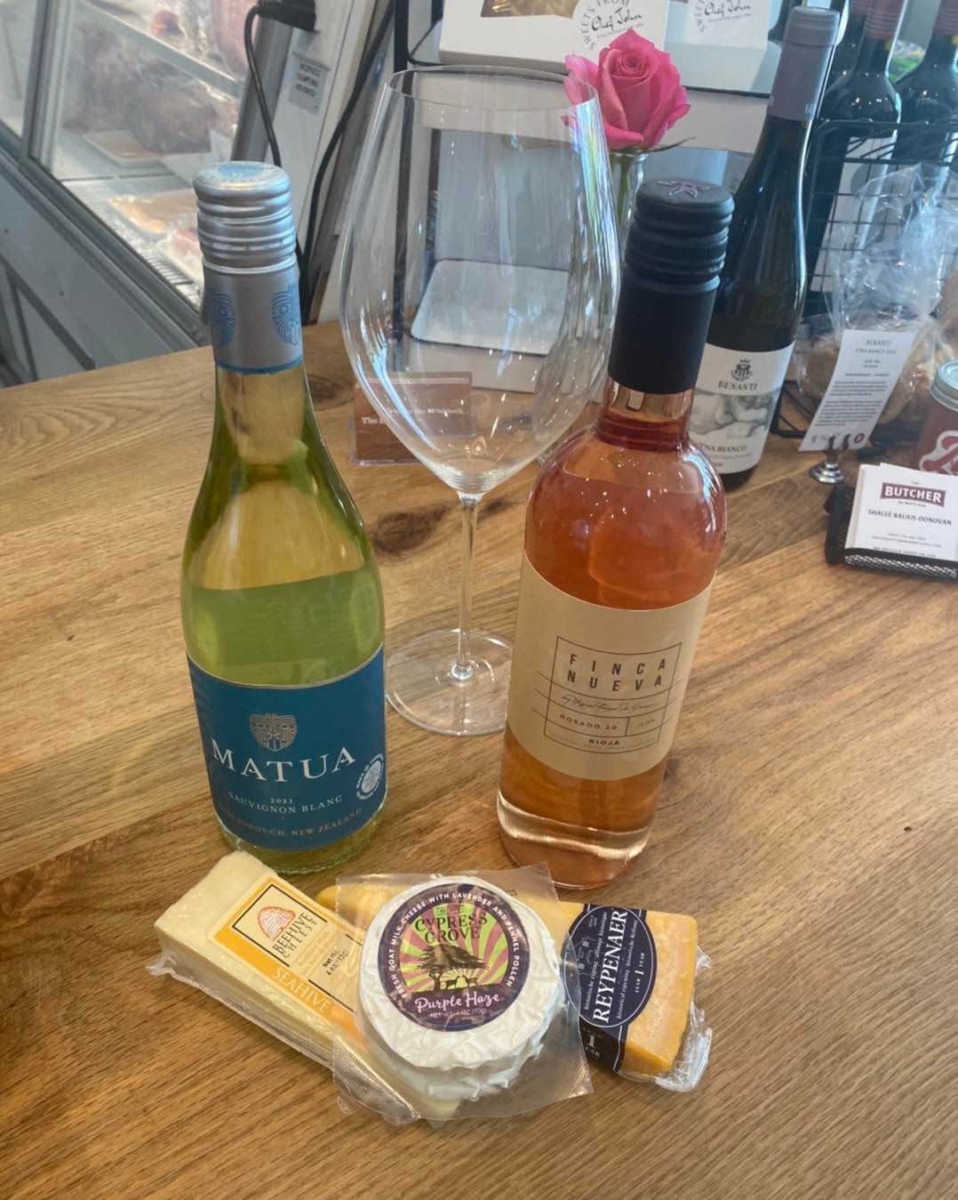 A bottle of wine and a glass of wine are on a wooden table.