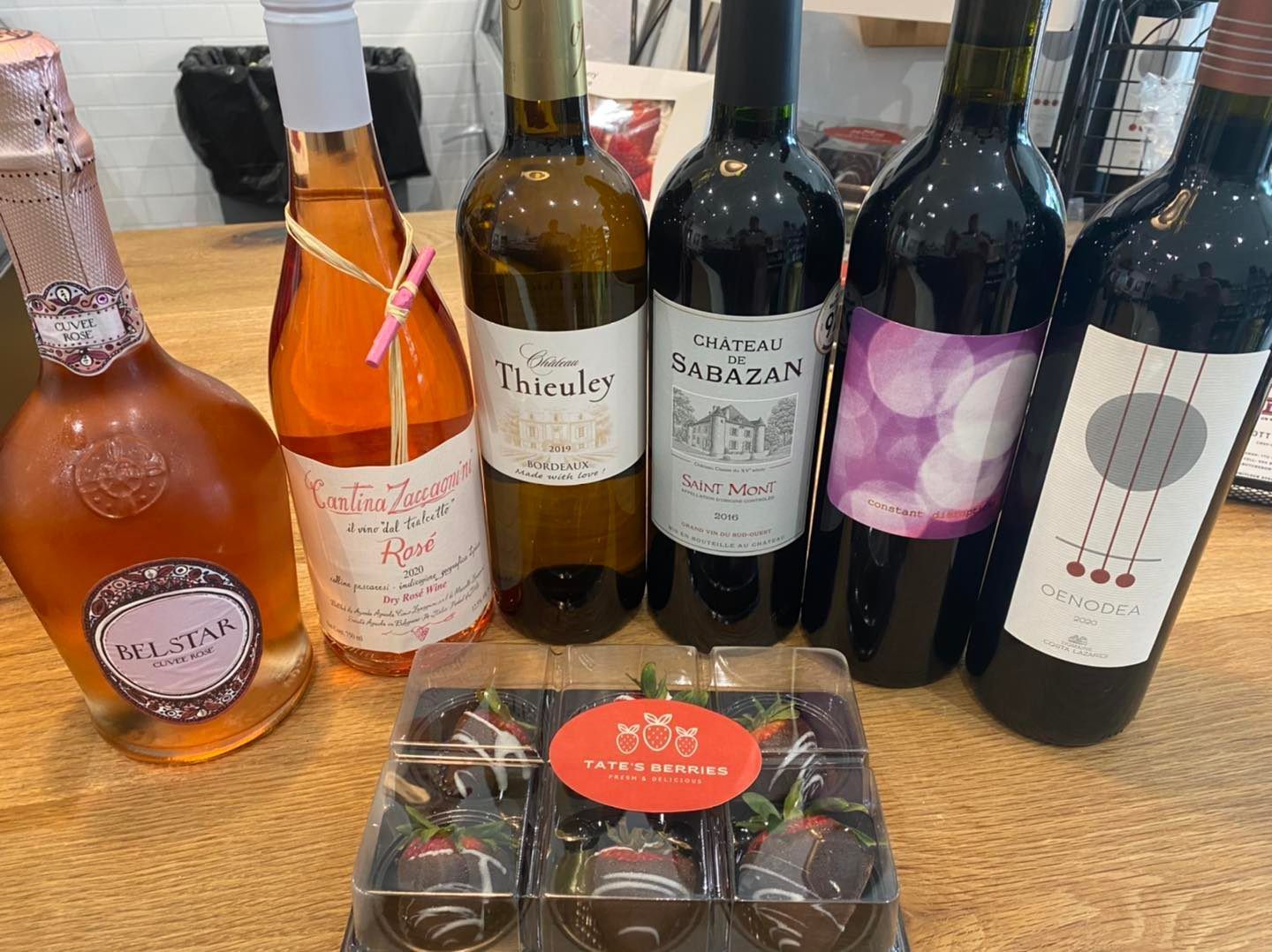 A table topped with bottles of wine and chocolate covered strawberries.