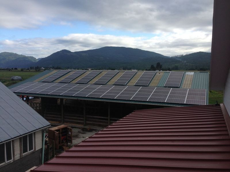Solar panels on a building roof with mountain backdrop.