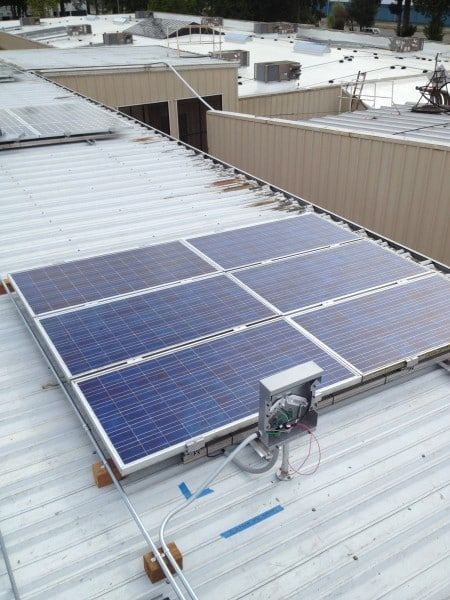 Solar panels installed on a white metal roof. Electrical box and wires visible.