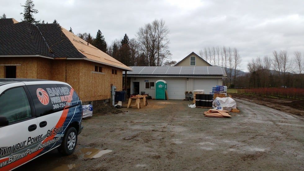 Construction site with unfinished buildings, a van, and a portable toilet on a cloudy day.