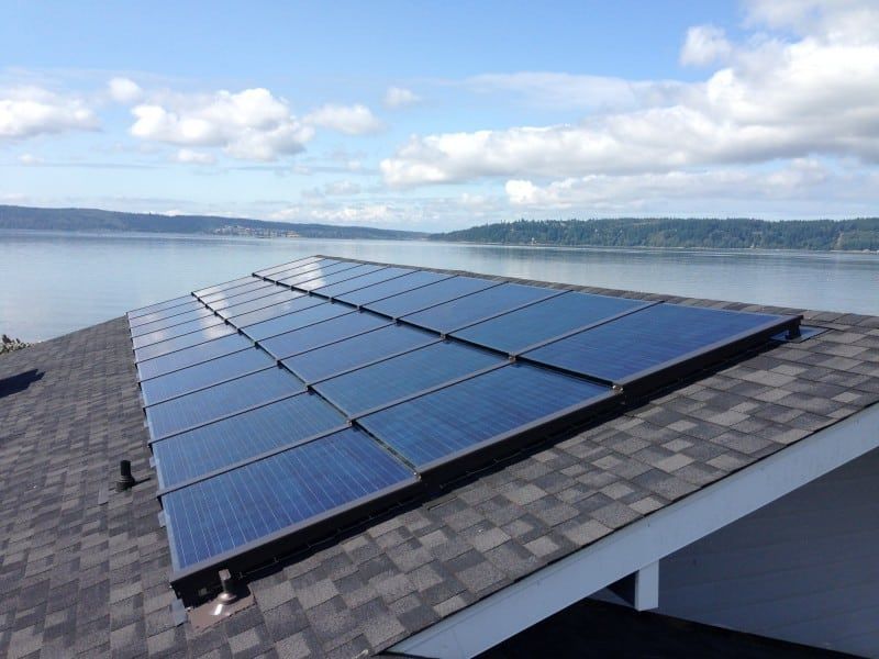 Solar panels installed on a roof with a water view and a cloudy sky.