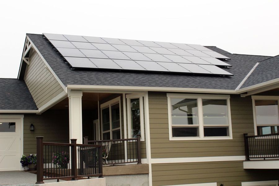 Solar panels on a residential roof, overlooking a porch and siding with windows.