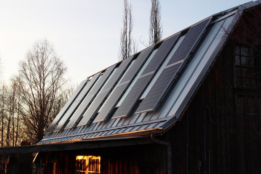 Solar panels installed on a metal roof of a weathered barn.