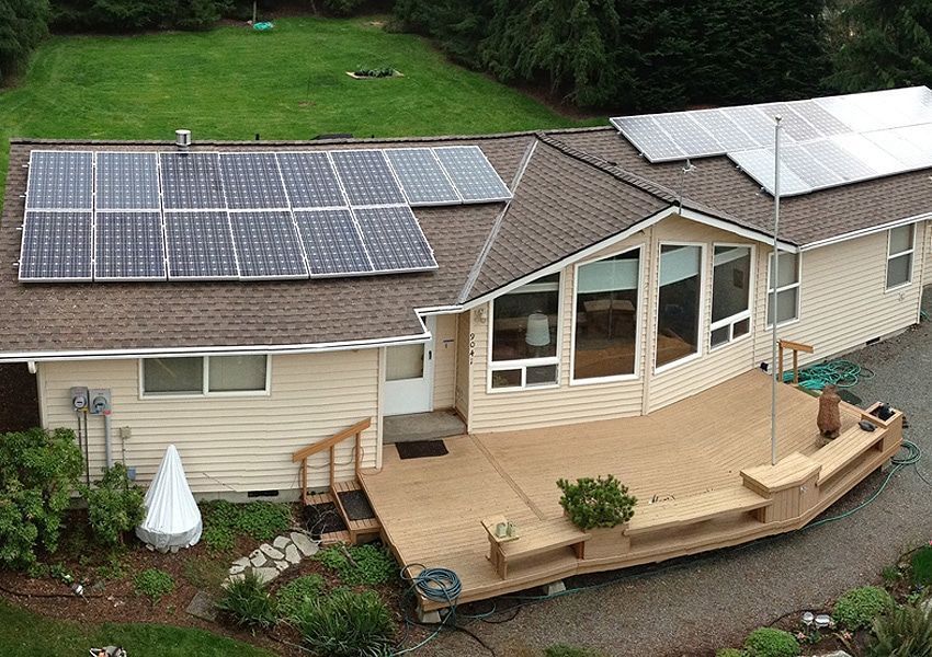 House with solar panels on roof and large wooden deck.