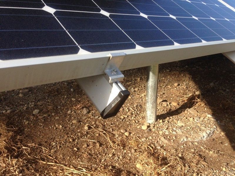 Solar panel attached to a metal frame, mounted on a stand above bare earth.