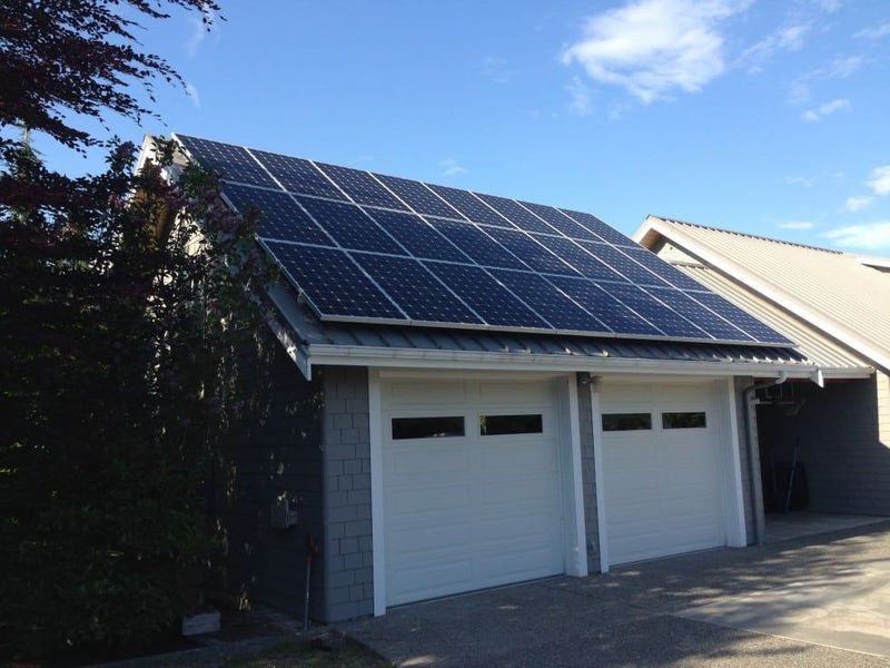 Solar panels on a garage roof under a blue sky.