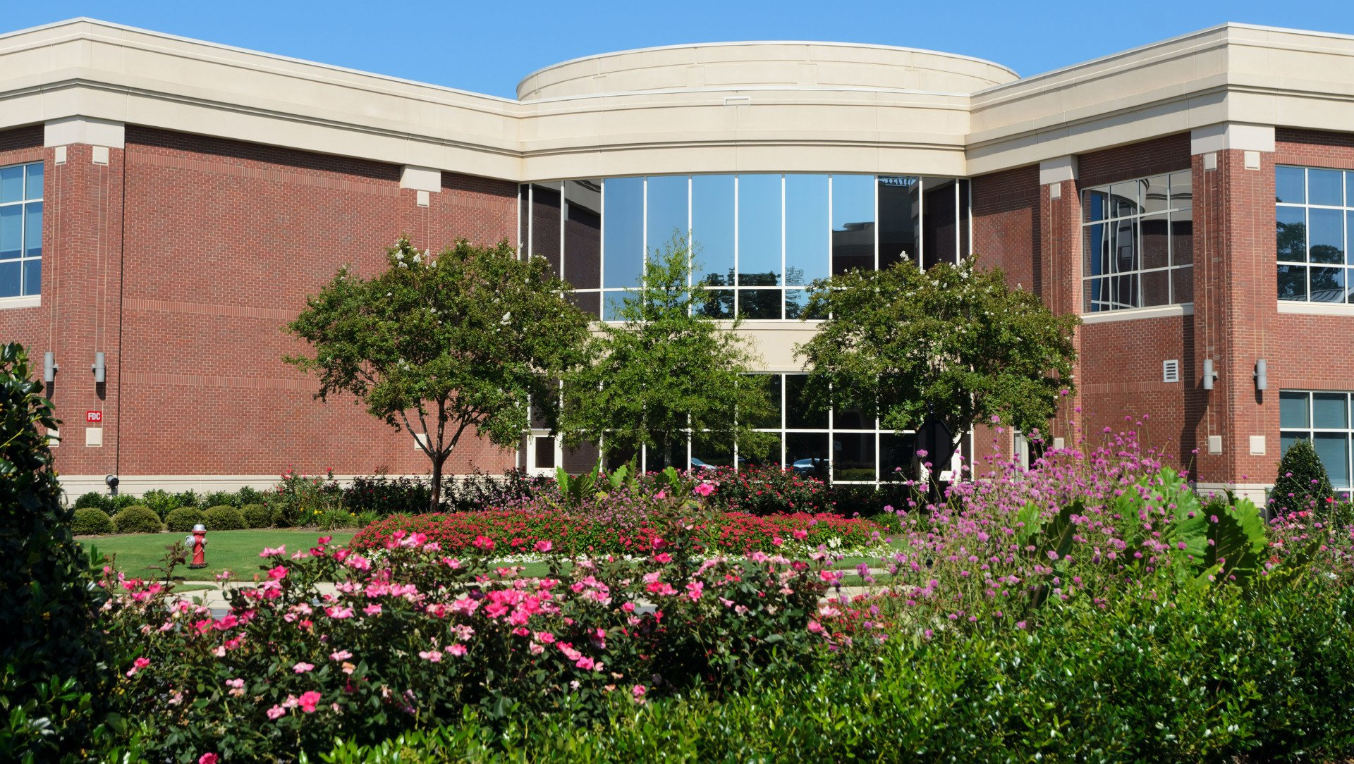 A large brick building with a lot of windows and flowers in front of it