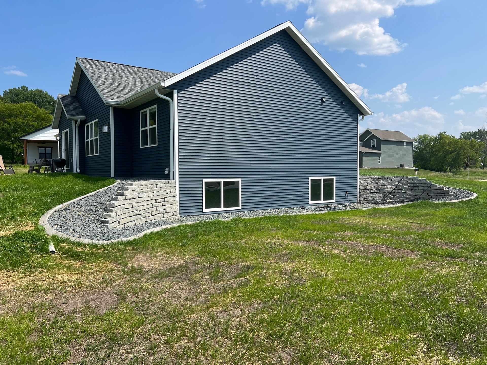 A house with a lot of windows is sitting on top of a lush green field.