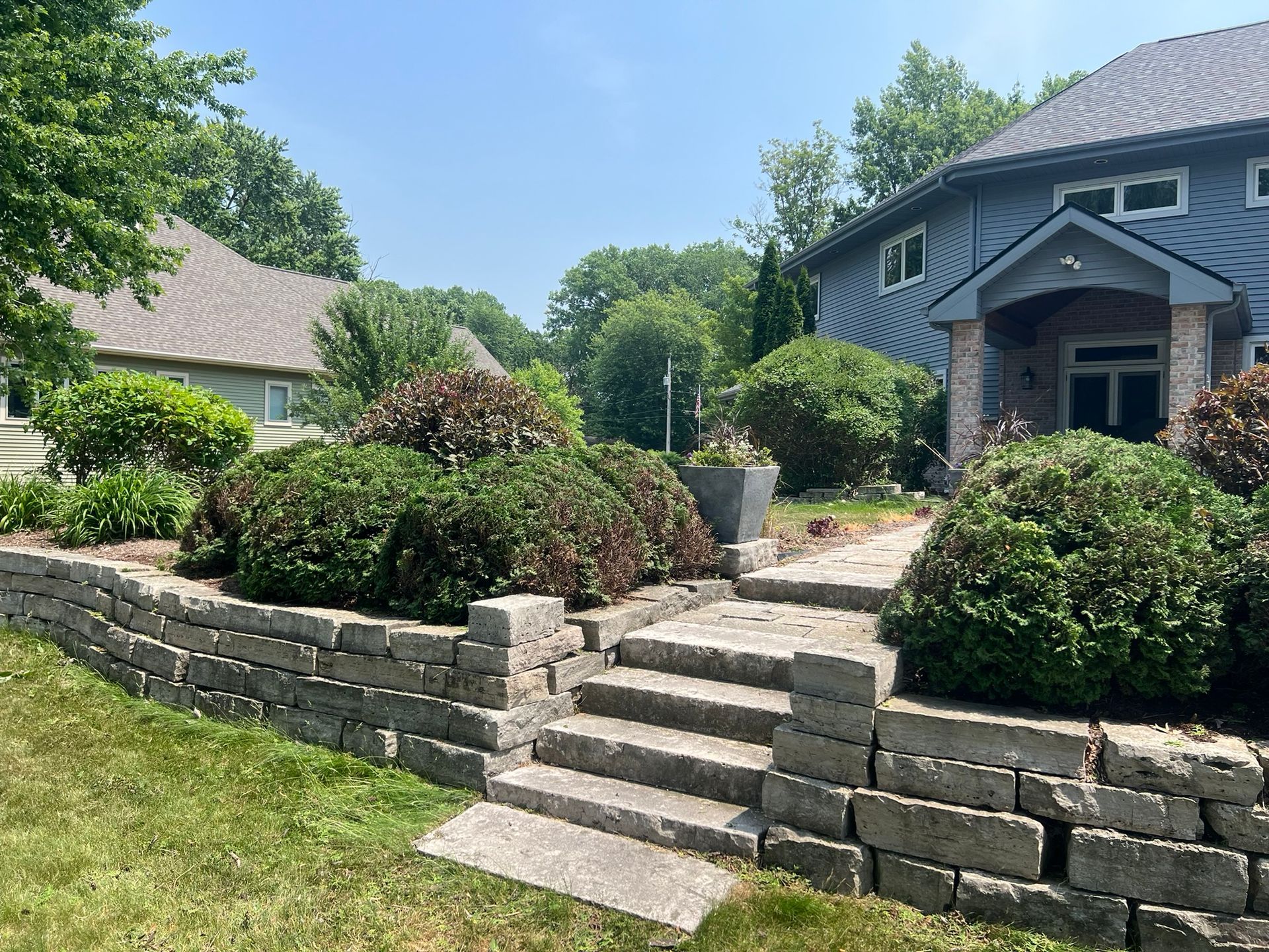 A house with a stone wall and stairs in front of it.