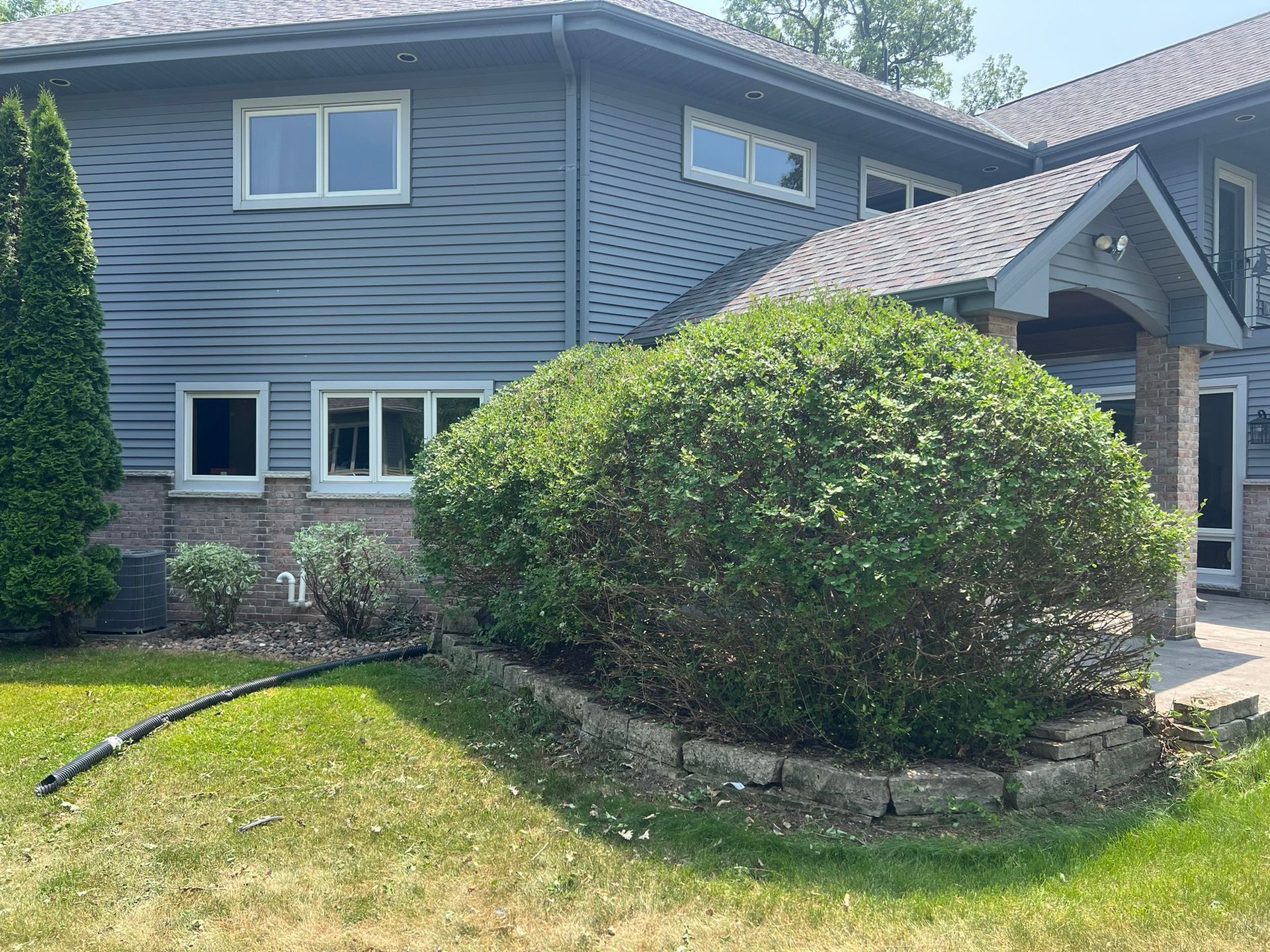 A large house with a large bush in front of it.