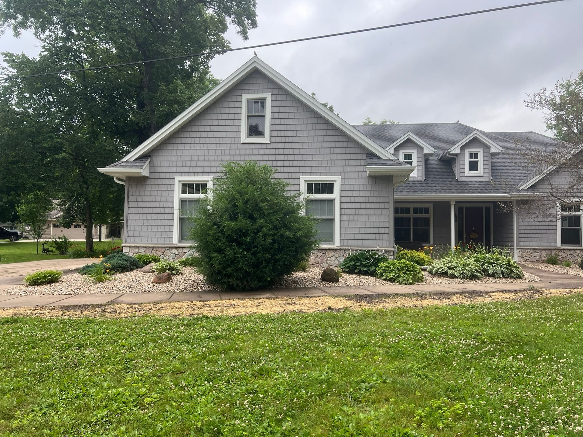 A gray house with a lot of windows is sitting on top of a lush green field.