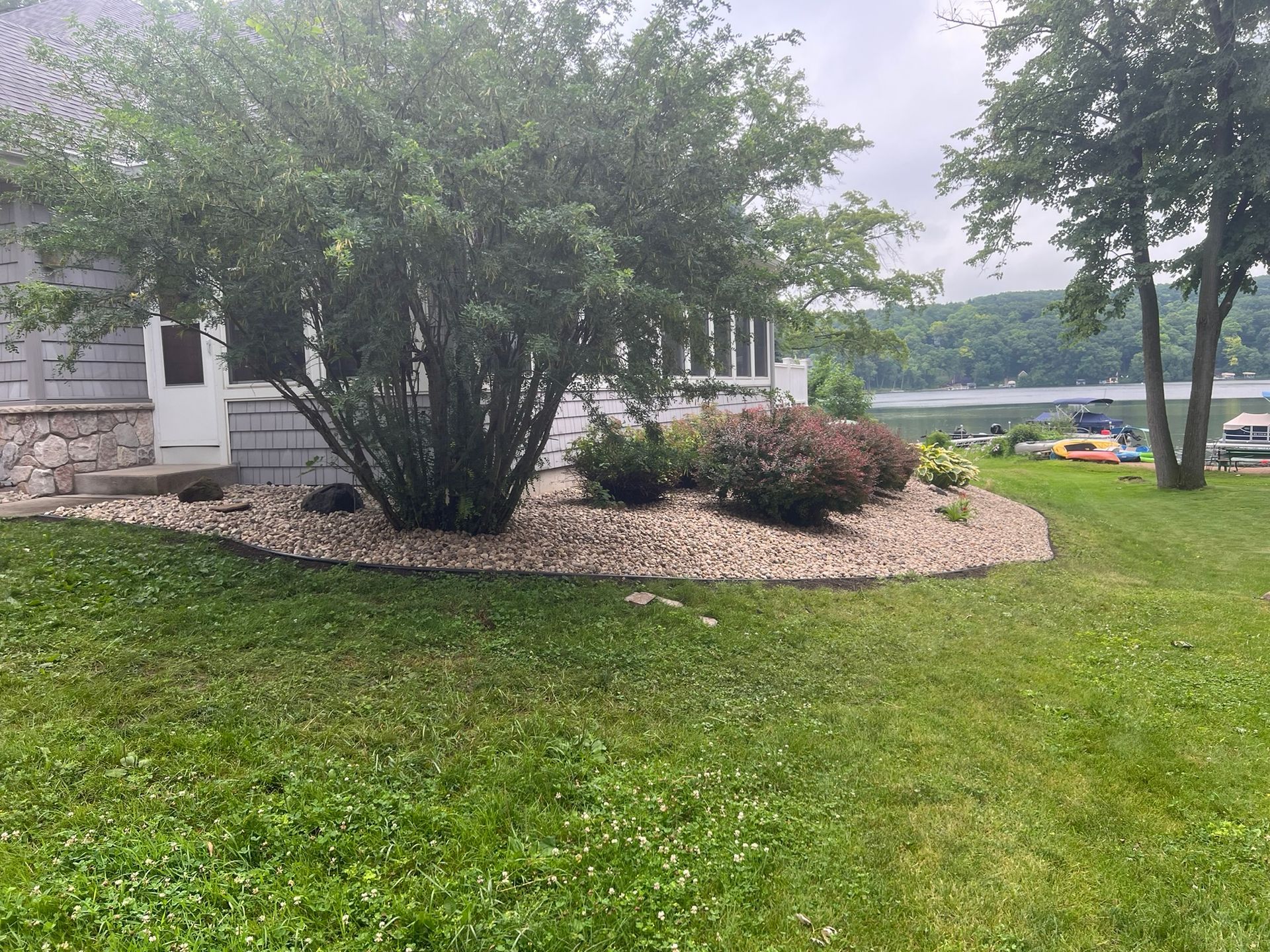 A house with a large lawn in front of it and a lake in the background.