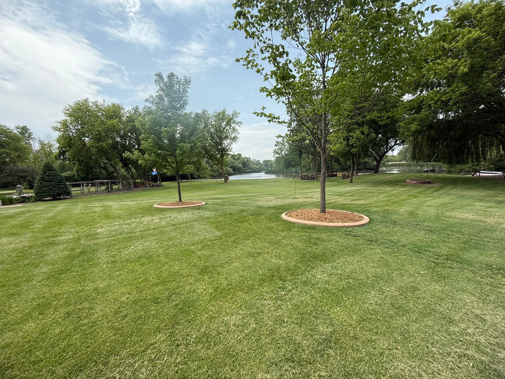A lush green field with trees and a lake in the background